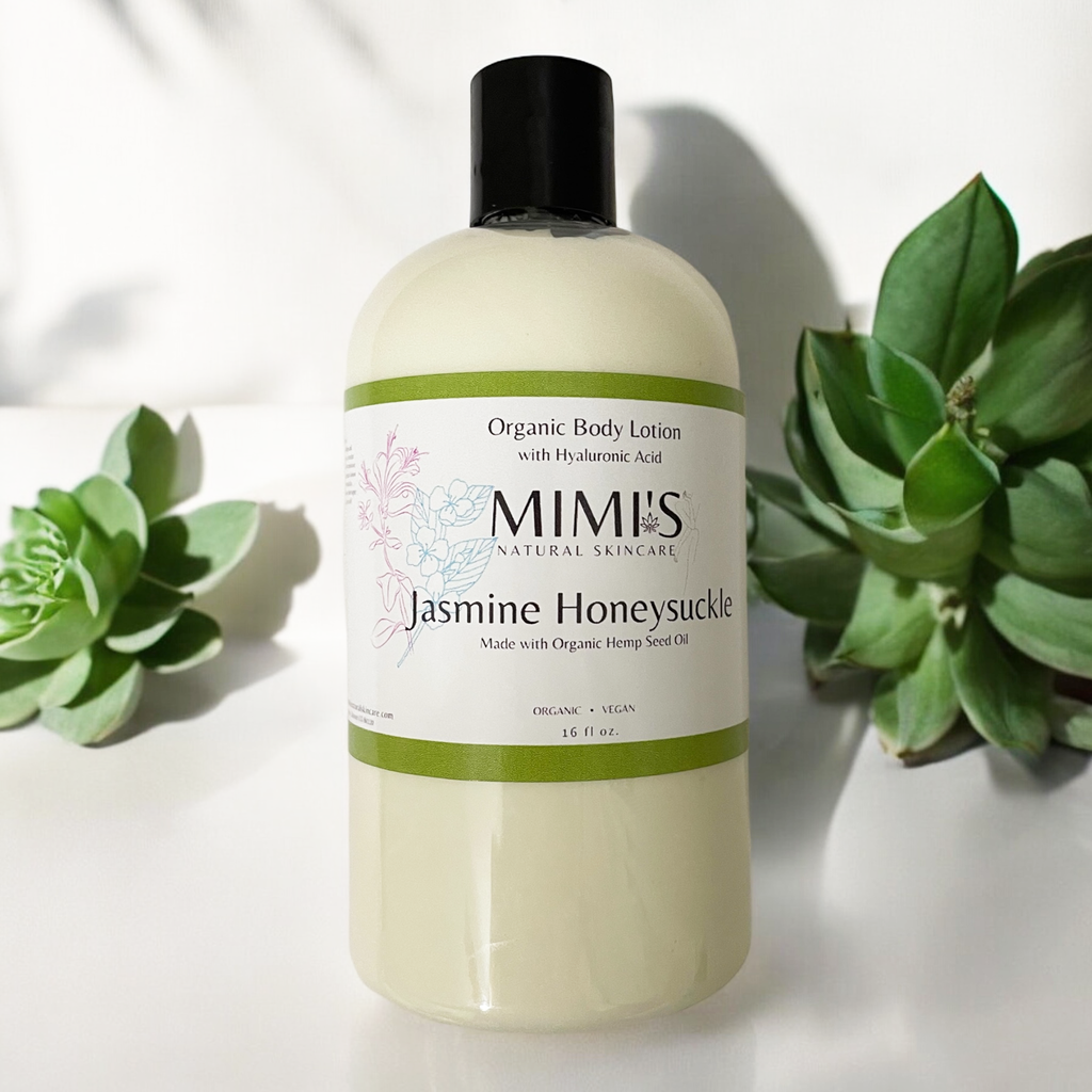 A bottle of organic body lotion with hyaluronic acid and wild rose, branded as MIMIS Natural Skincare, with a pump dispenser, placed next to green foliage.