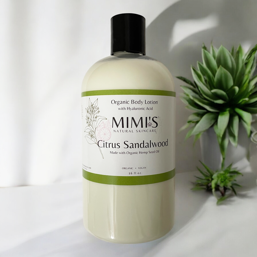 A bottle of MIMIS Natural Skincare Organic Body Lotion with Hyaluronic Acid, labeled 'Citrus Sandalwood', with a pump dispenser, placed on a white surface with a green cactus plant in the background.