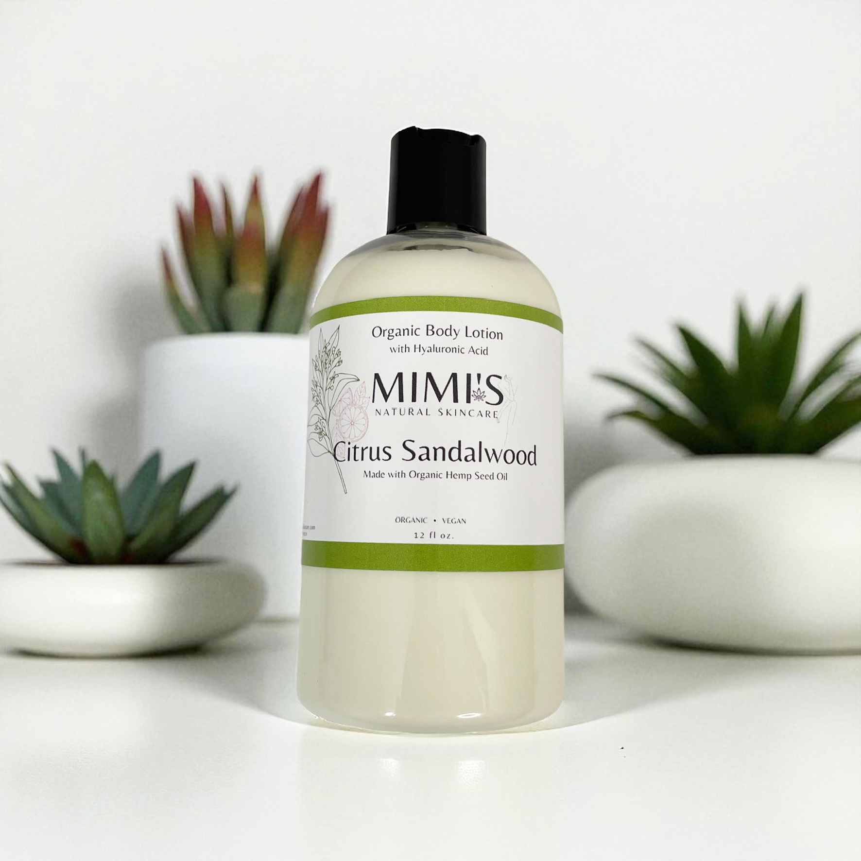 Bottle of Mimis Citrus Sandalwood organic body lotion with plants in the background