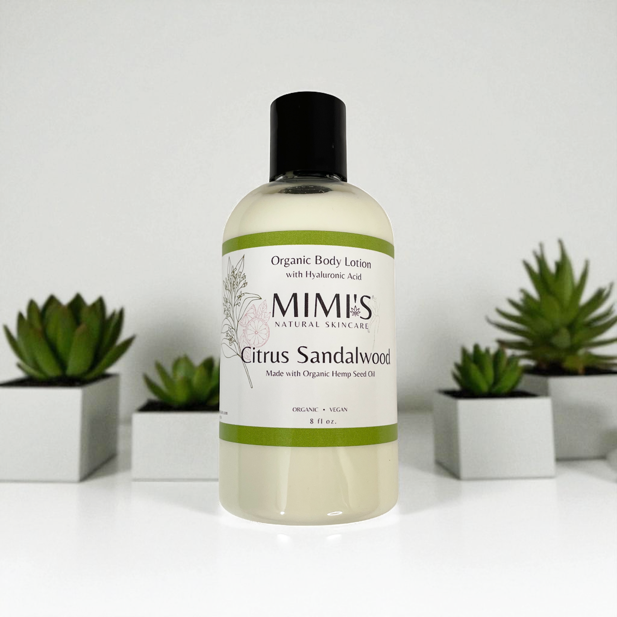 Bottle of MIMI's Citrus Sandalwood organic body lotion with plants in the background