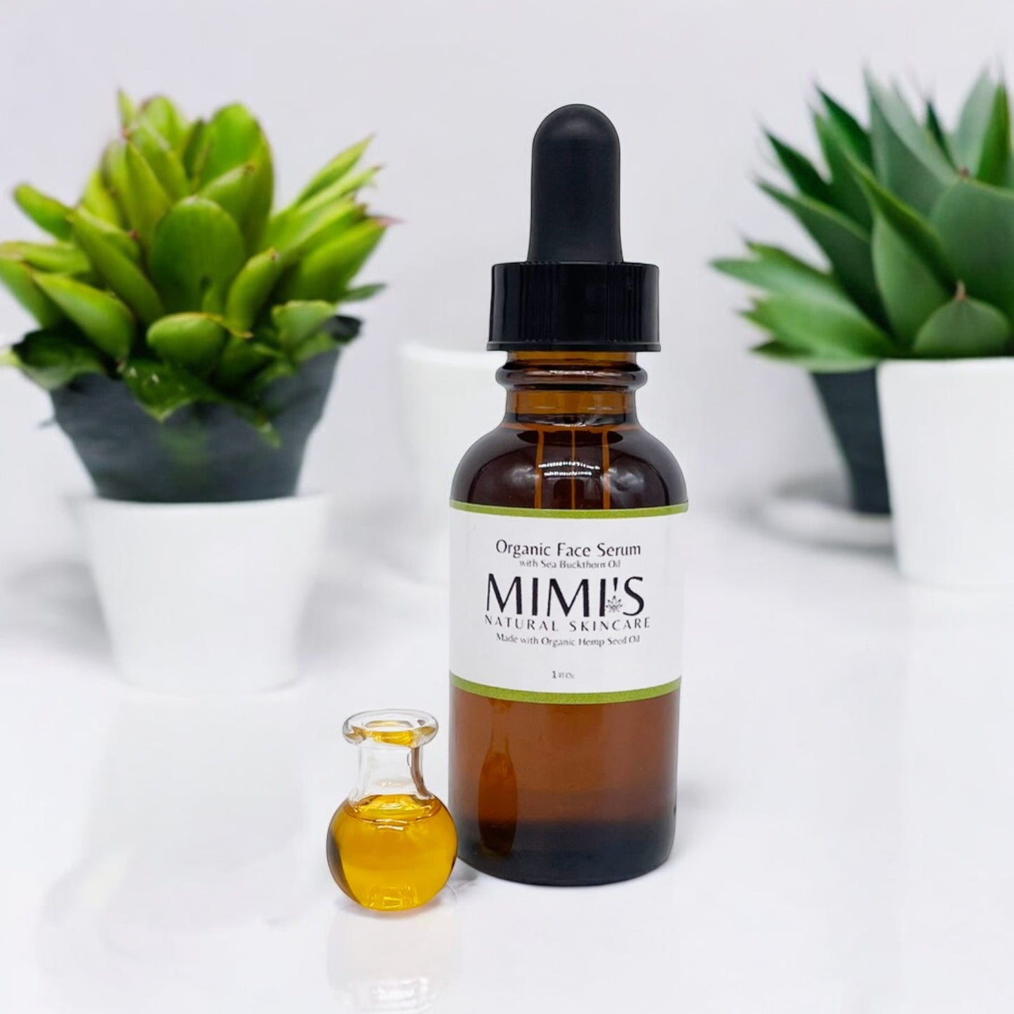Brown glass bottle with dropper labeled 'MIMI'S' on a white background with green plants.